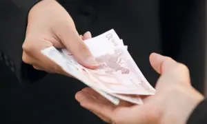 Dwie dłonie przekazują sobie banknoty euro. Zastanawiasz się, ile kosztuje windykacja należności?