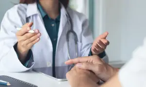Lekarz w białym kitlu rozmawia z pacjentem, omawiając jego stan. Pytanie, czy rehabilitant może wystawić L4, jest kluczowe dla wielu osób.