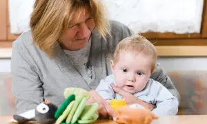 Babcia z czułością opiekuje się wnukiem, pokazując mu zabawki.