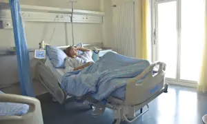 Młoda kobieta leży w szpitalnym łóżku, zastanawiając się, **l4 co to** za choroba ją dopadła.