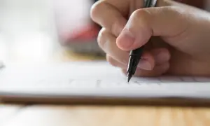 Dłoń pisze piórem po papierze. Czy można skończyć technikum bez egzaminu zawodowego? Zastanawiam się nad tym, wypełniając dokumenty.
