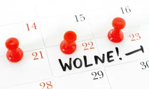 Kalendarz z zaznaczonym dniem wolnym. Czerwone pinezki oznaczają daty, a na 22. widnieje napis "WOLNE!".