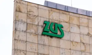 Zielone logo ZUS na beżowej, kamiennej fasadzie budynku.