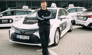 Młody kierowca Ubera z dumą pozuje przy białych autach. Zastanawiasz się, ile można zarobić w Uberze?
