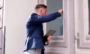 Mężczyzna w garniturze puka do drzwi, trzymając teczkę. Czy windykator może przyjść w sobotę?
