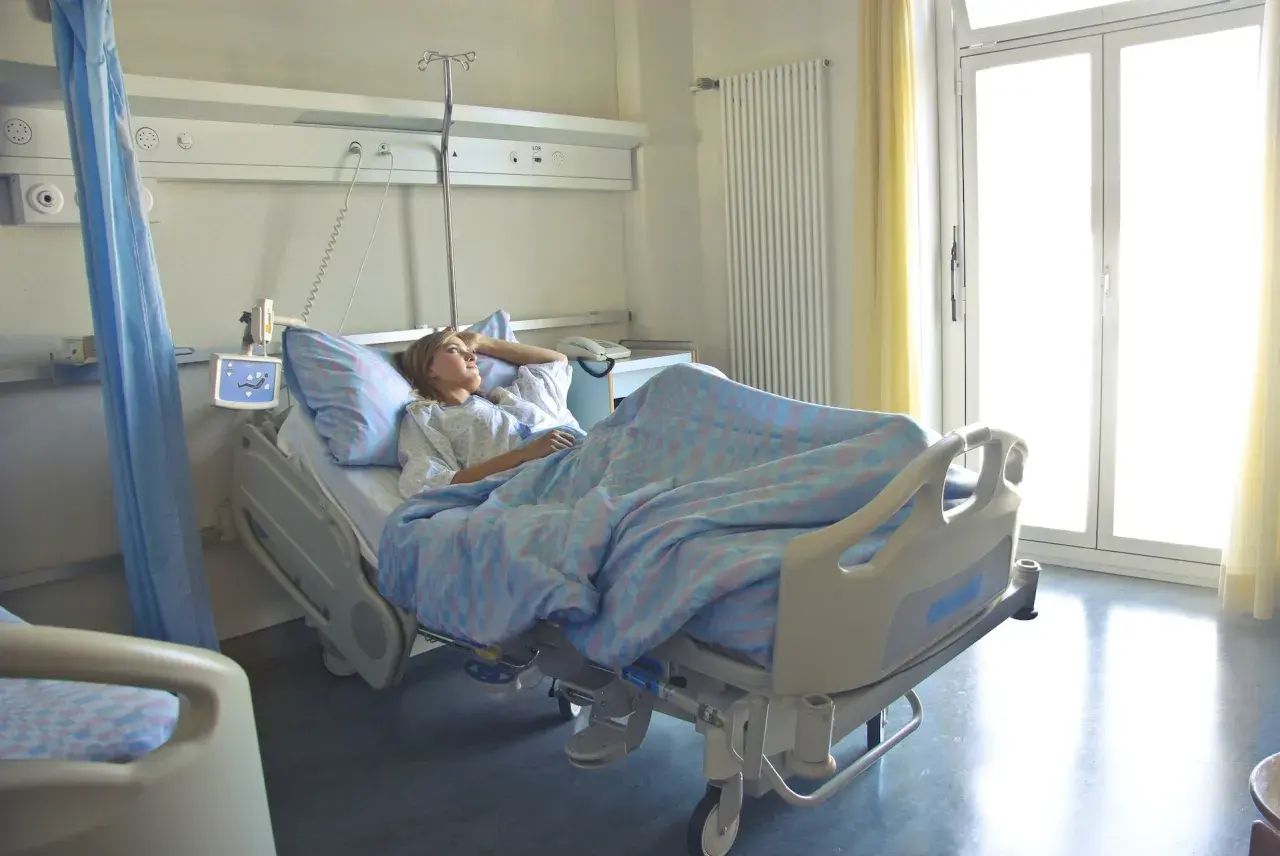 Młoda kobieta leży w szpitalnym łóżku, zastanawiając się, **l4 co to** za choroba ją dopadła.