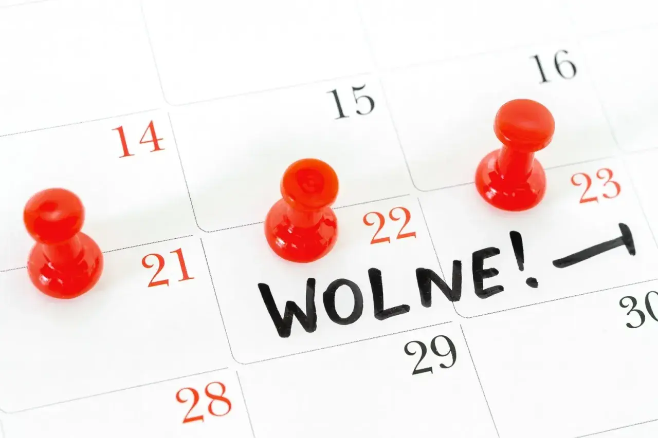Kalendarz z zaznaczonym dniem wolnym. Czerwone pinezki oznaczają daty, a na 22. widnieje napis "WOLNE!".
