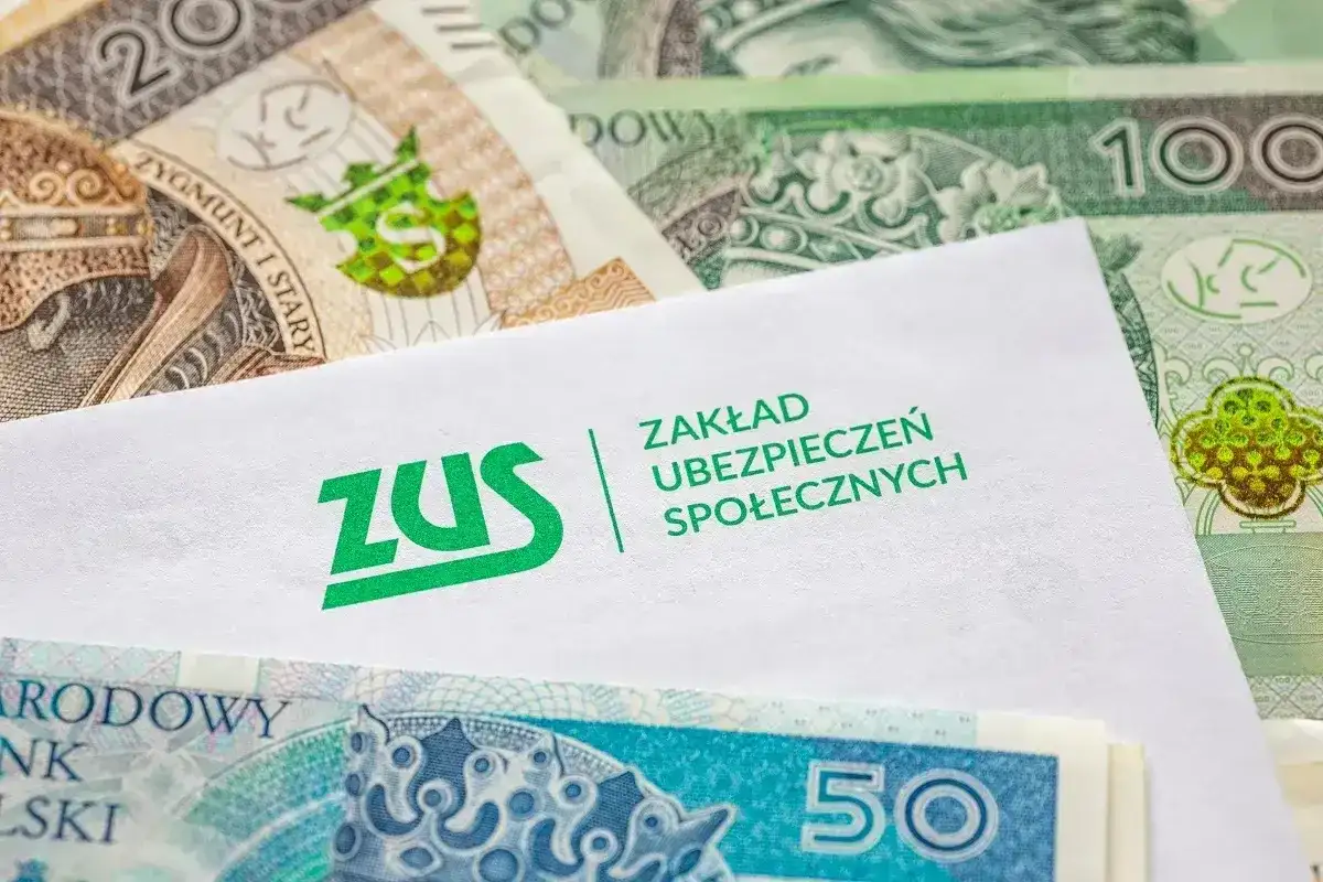 Kiedy ZUS wypłaca L4, pieniądze w postaci polskich banknotów leżą obok koperty z logo ZUS.