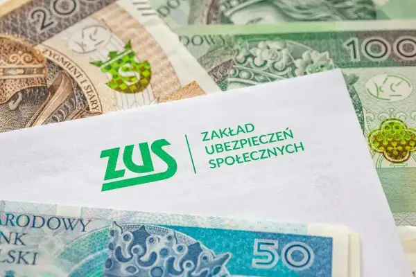 Kiedy ZUS wypłaca L4, pieniądze w postaci polskich banknotów leżą obok koperty z logo ZUS.