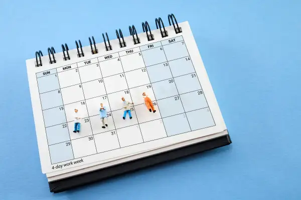 Figurki ludzi na kalendarzu z napisem "4-day work week". Pomaga to zrozumieć, jak wyliczyć średnioroczne zatrudnienie.