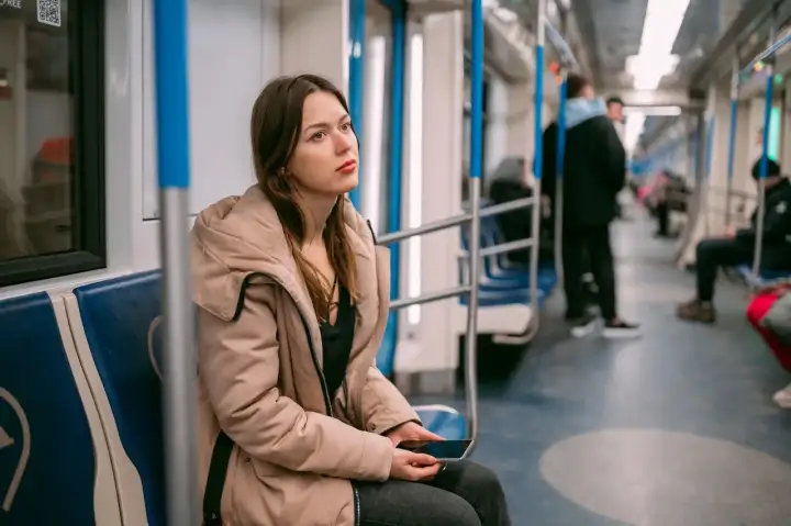 Młoda kobieta w beżowej kurtce siedzi w metrze, zamyślona. Może właśnie wraca z wizyty u lekarza, który wystawił jej zwolnienie lekarskie z powodu wypalenia zawodowego.